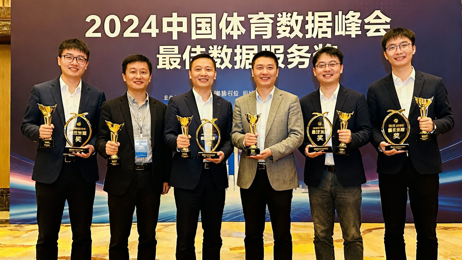 悟空体育技术团队在2024中国体育数据峰会颁奖典礼上的合影，团队成员手持最佳数据服务奖奖杯，面带笑容站在背景板前